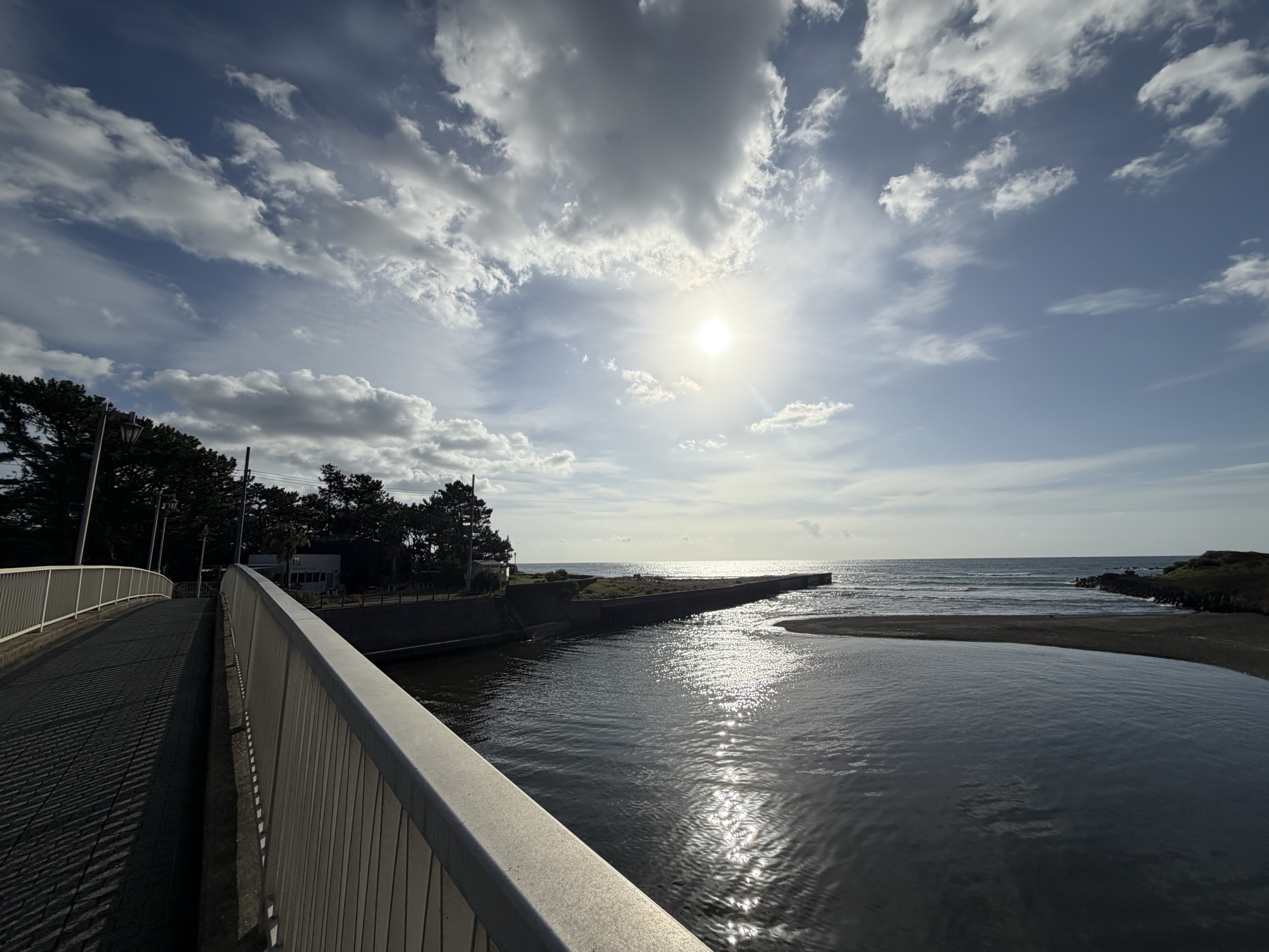 朝の光が映る川と、その先の海
